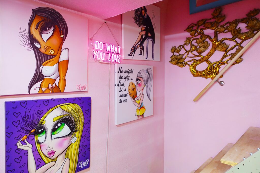 Interior view of Just Browzin' lash studio in Toledo, Ohio, featuring light pink walls, custom lash-themed pop art, and a "DO WHAT YOU LOVE" neon sign, reflecting a vibrant and inviting atmosphere.
