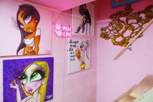 Interior view of Just Browzin' lash studio in Toledo, Ohio, featuring light pink walls, custom lash-themed pop art, and a "DO WHAT YOU LOVE" neon sign, reflecting a vibrant and inviting atmosphere.